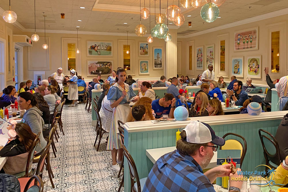 Guests sitting at tables and booths at the Beaches and Cream Soda Shop at the Disney Beach Club Resort 1000