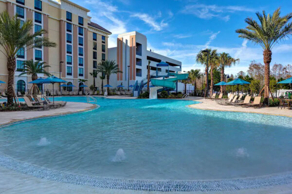 Large Outdoor Pool with zero-entry and water slide in background at the Home2 Suites in Flamingo Crossing a Hilton Hotel 1000