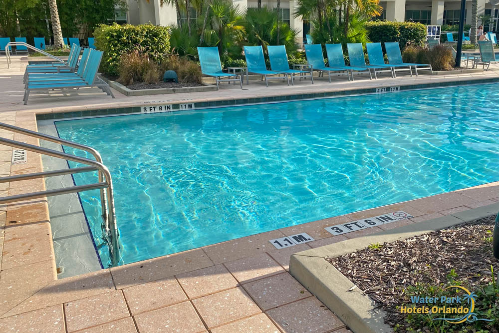 Outdoor pool with steps on one end and seating around the edge at the TownPlace Suites in Flamingo Crossing 1000