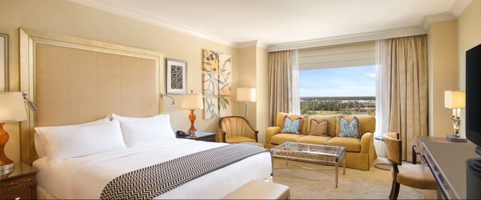 View of a Deluxe King Room with Large Bed space for Living area with Sofa and Chairs with Picture Window at the Waldorf Astoria Orlando
