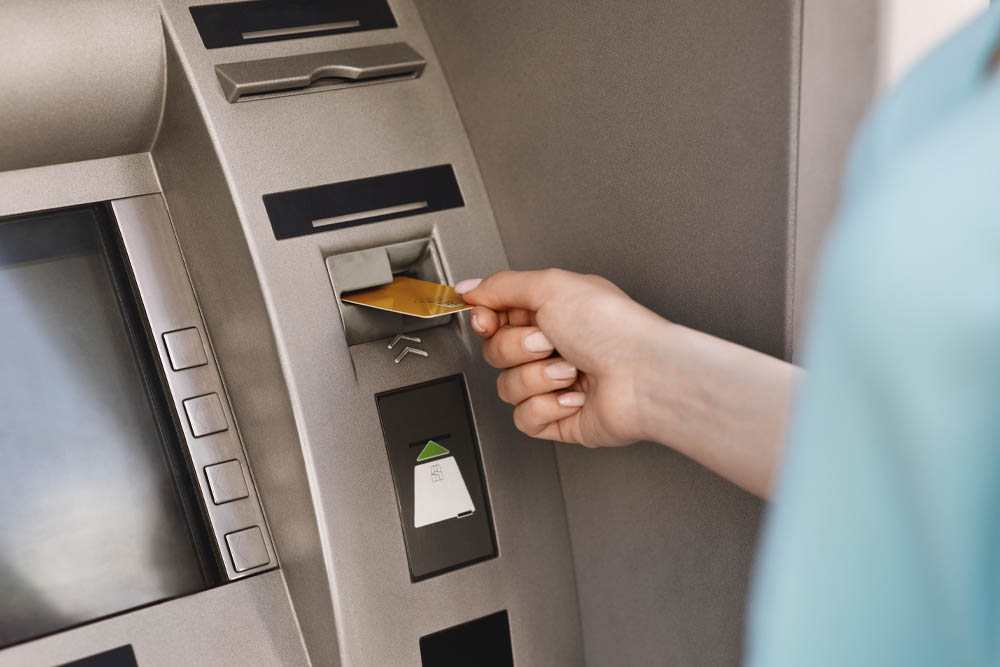 Woman inserting card into ATM machine 1000