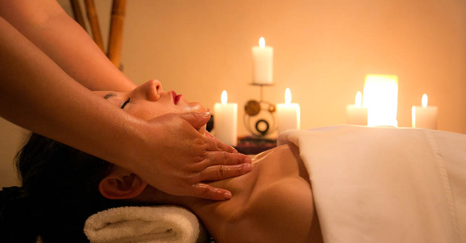 Woman on table laying on back getting a massage with candles in the background 960