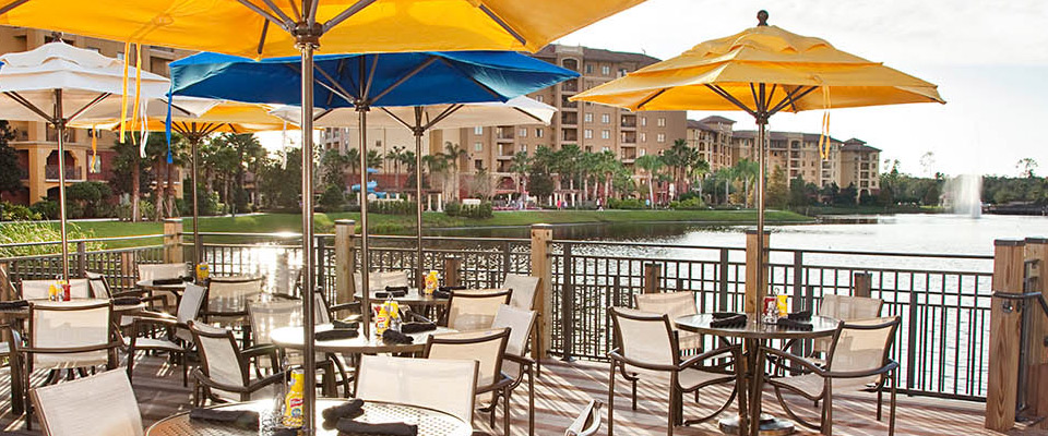 View of a Tables with Umbrellas for light dining on the lake beside the main outdoor pool Back Bay Bar and Grill at the Grand Cypress Hyatt Orlando