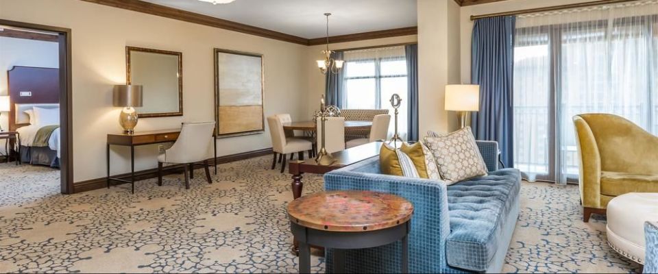 A very large living space with plenty of seating looking in to the private bedroom of the Junior Presidential Suite at the Wyndham Grand Orlando